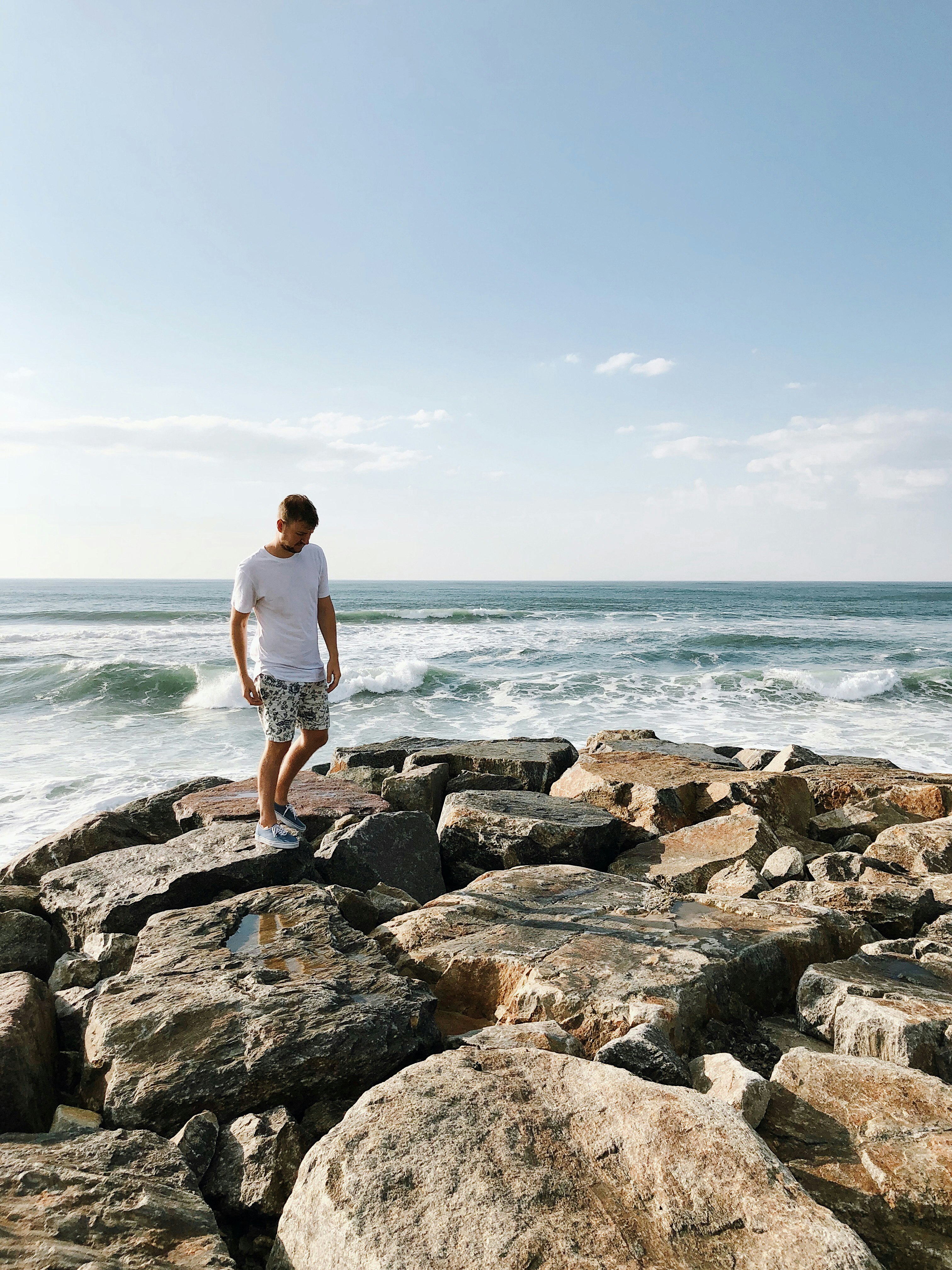 man standing on rocks near body of water